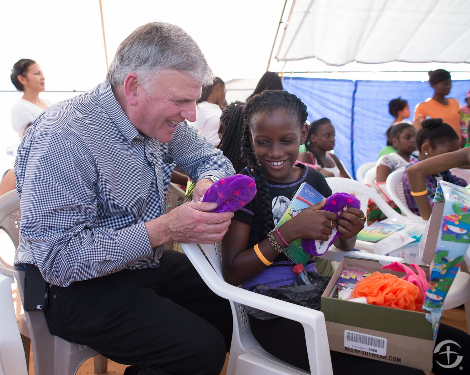 Franklin Graham watches a young girl open her shoebox. Image courtesy of Samaritan's Purse.